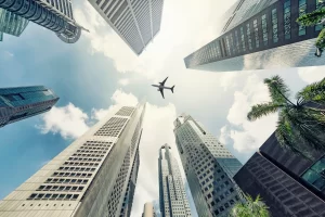 An image that looks up between buildings in Singapore to an aircraft flying overhead.